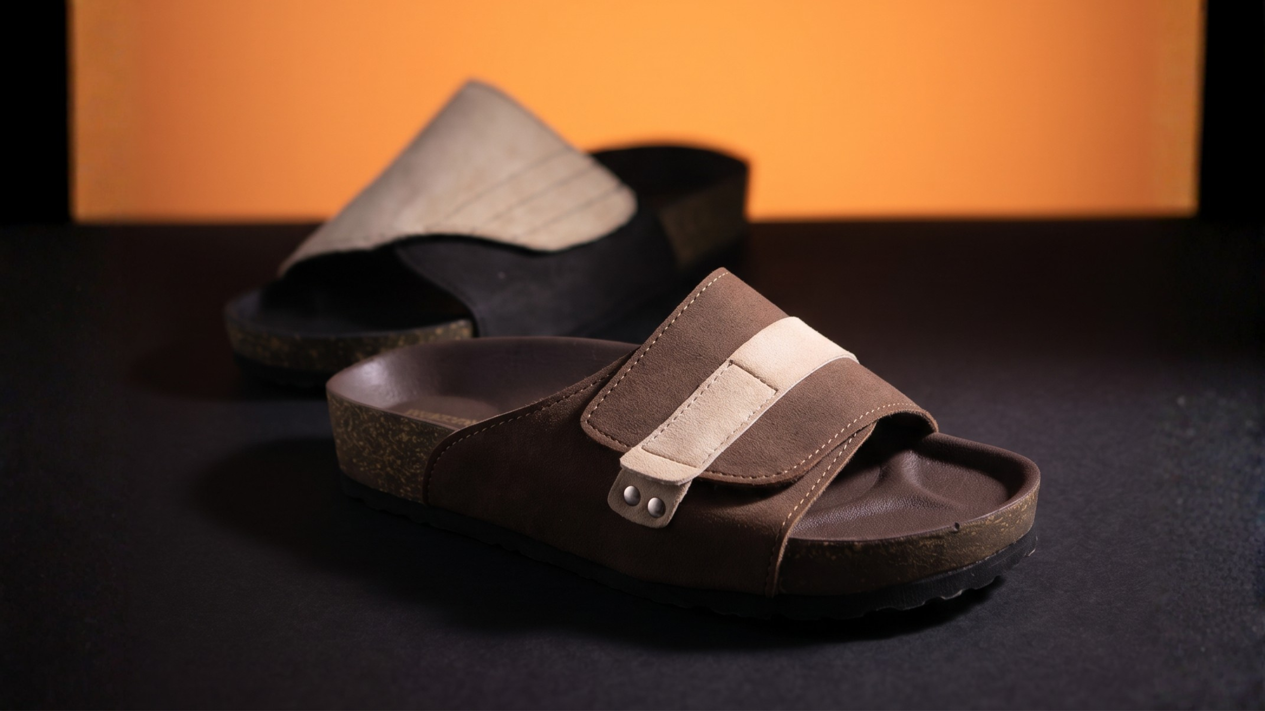 A pair of slide sandals with a flower in the background.