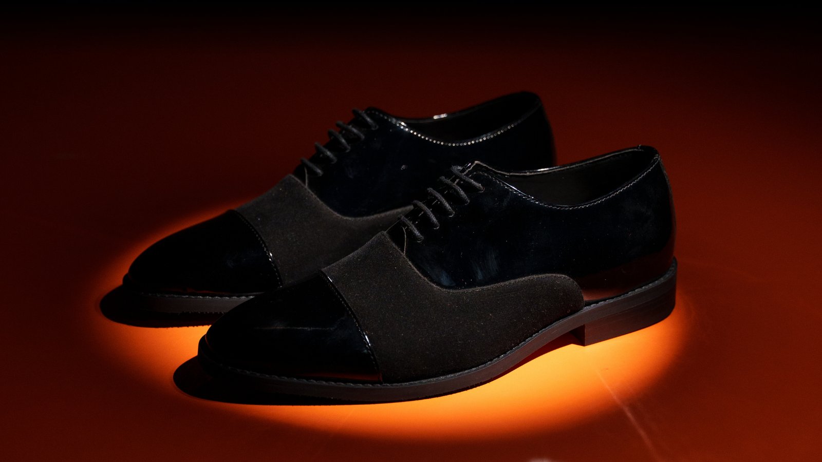 A pair of black shoes on a black background.